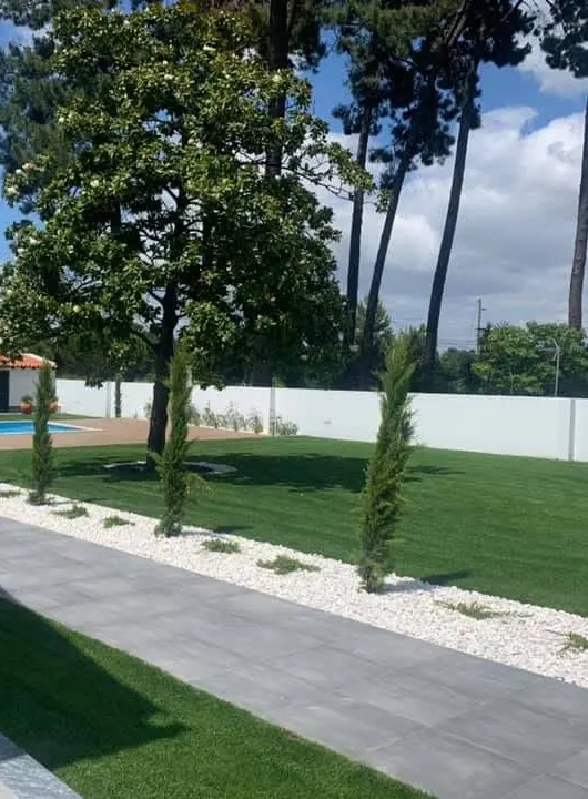 Caminho em lajeta, gravilha branca e relvado, com a piscina ao fundo, depois da obra.