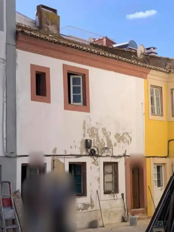 Antes da obra: fachada de dois pisos com reboco a cair e molduras cor de laranja.
