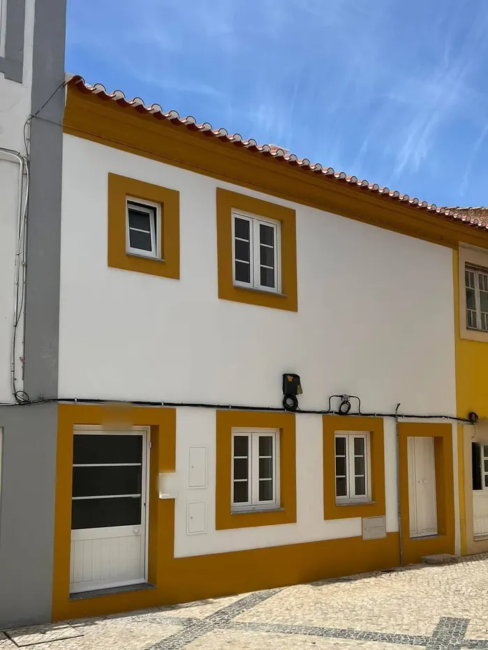 Depois da obra: a mesma fachada pintada de branco, com molduras e soco cor de mostarda.