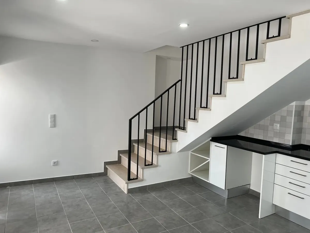 Depois da obra: rés do chão com escada em pedra, guarda metálica e cozinha por baixo.